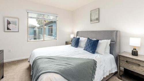 1 dormitorio blanco con 1 cama grande con almohadas azules en Landing Modern Apartment with Amazing Amenities (ID7594X27) en San Diego