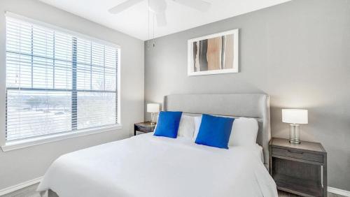 een slaapkamer met een wit bed met blauwe kussens bij Landing Modern Apartment with Amazing Amenities (ID7966X24) in Lewisville