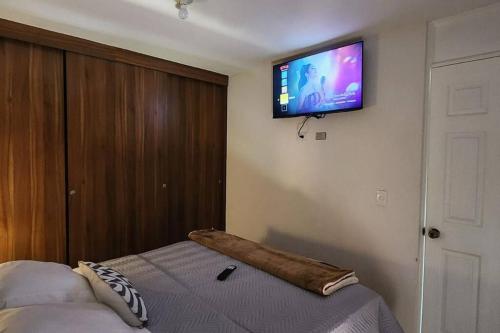 um quarto com uma cama e uma televisão de ecrã plano na parede em Apartamentos de la Rosa -Departamento Nuevo em Cobán
