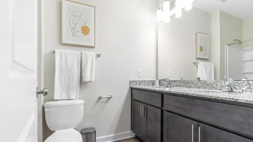 Baño blanco con aseo y lavamanos en Landing Modern Apartment with Amazing Amenities (ID1012X166), en Clayton
