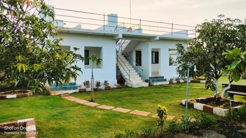 ein weißes Haus mit Rasen davor in der Unterkunft AamraKunj Gir Resort in Sasan Gir