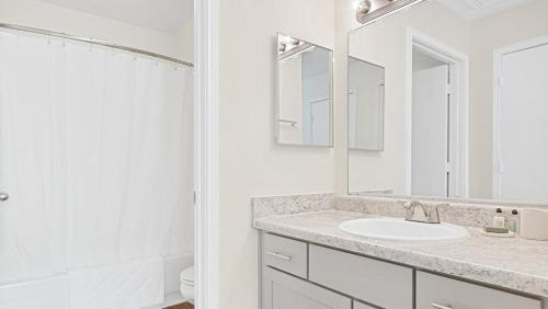 bagno bianco con lavandino e specchio di Landing Modern Apartment with Amazing Amenities (ID6949X45) a Winston-Salem