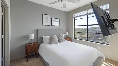 a bedroom with a white bed and a flat screen tv at Landing Modern Apartment with Amazing Amenities (ID4310X3) in Orlando