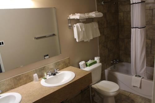 La salle de bains est pourvue d'un lavabo, de toilettes et d'une baignoire. dans l'établissement Travelodge by Wyndham Swift Current, à Swift Current