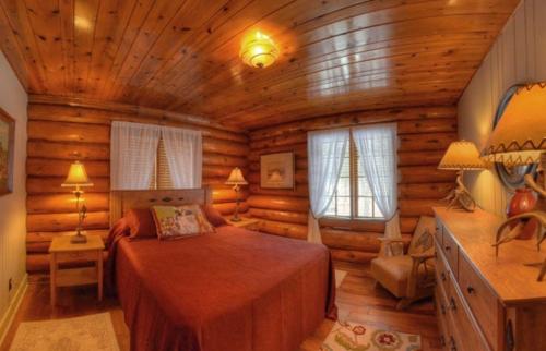 1 dormitorio con 1 cama en una cabaña de madera en Historic Log Cabin #14 at Horse Creek Resort en Rapid City