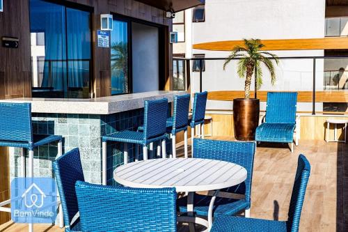 eine Terrasse mit blauen Stühlen, einem Tisch und einer Theke in der Unterkunft Apartamento aconchegante na Barra com vista mar in Salvador