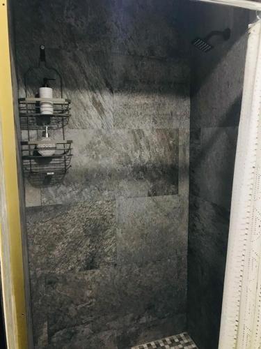 a shower in a bathroom with a stone wall at HOTEL and Suites Cananea in Cananea