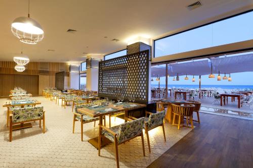 TRS Yucatan Hotel - Adults Only في أكومال: مطعم به طاولات وكراسي ومطل على المحيط