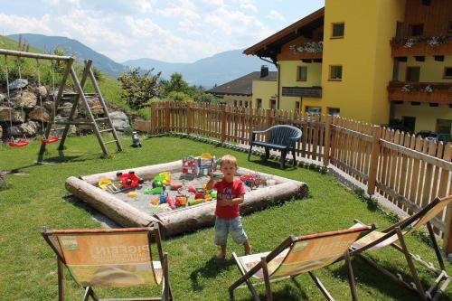 a young boy standing in a sandbox in a yard at Ferienhotel Samerhof in Pfarrwerfen