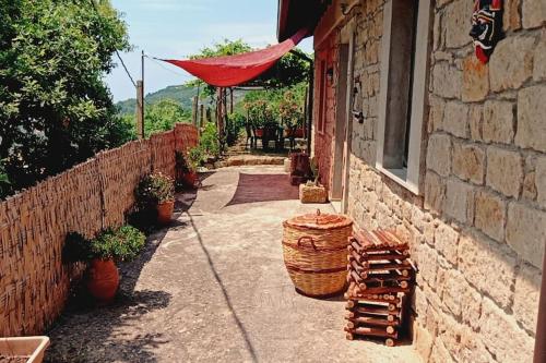 ein Steingebäude mit einer Terrasse mit einem roten Regenschirm in der Unterkunft Atelier.Germana in CastellʼUmberto Vecchio
