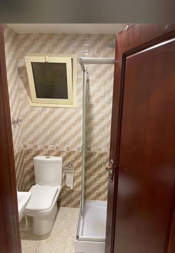 a bathroom with a toilet and a television on the wall at فندق العنقود - قريش in Jeddah