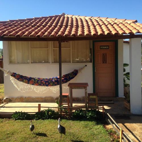a house with a hammock and two birds in the yard at Pouso dos Querubins in Tiradentes