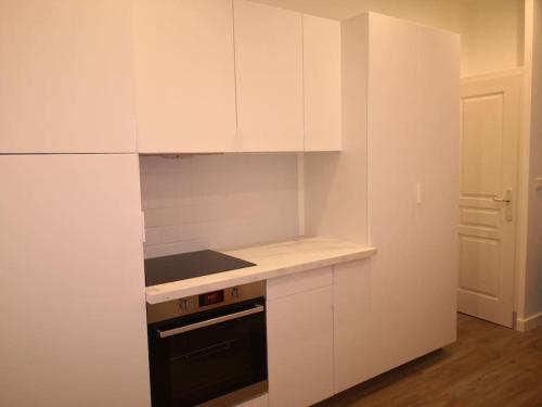 - une cuisine avec des placards blancs et une cuisinière noire dans l'établissement Studio idéalement placé, à Ajaccio