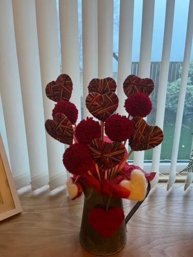 a vase filled with red flowers and hearts at Bees cottage Luxury 5* Holiday cottage with Hot Tub in Scarborough