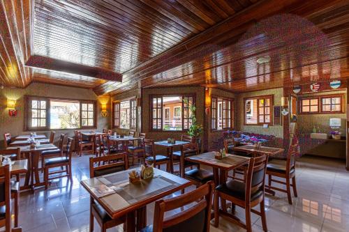 a restaurant with wooden tables and chairs and windows at Pousada Saint Gallen in Campos do Jordão