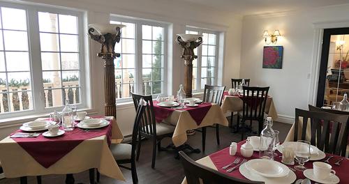 a dining room with tables and chairs and windows at Auberge La Daïna in Baie-Saint-Paul