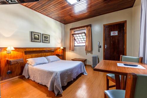Un dormitorio con una cama y una mesa. en Pousada Saint Gallen, en Campos do Jordão