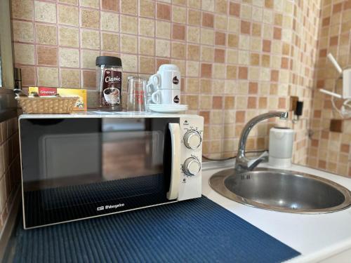 um micro-ondas num balcão de cozinha ao lado de um lavatório em Hostal La Campiña em Ronda