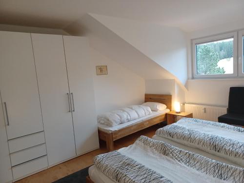 una camera mansardata con due letti e una finestra di Haus Lucia, mit Pool und Sauna, Appartment 4 a Schönwald