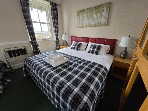 a bedroom with a large bed with a plaid blanket at The National Hotel in Dingwall