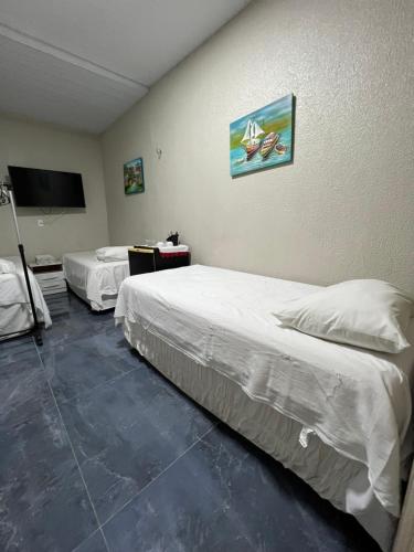 a room with two beds and a flat screen tv at Pousada da Celma in Fortaleza