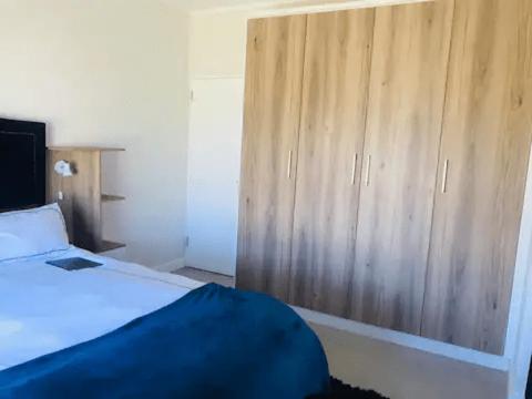 a bedroom with a bed and a wooden cabinet at Luxurious Lifestyle in Cape Town