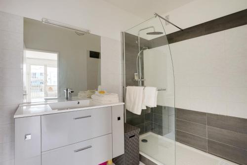 y baño blanco con lavabo y ducha. en CHAMPS DE MARS - SUFFREN, en París