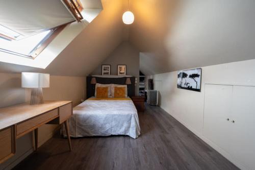 een slaapkamer met een bed en een bureau op zolder bij Bellevue sur Sèvres in Sèvres