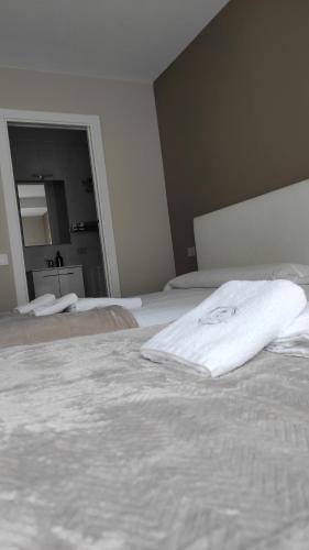 a bedroom with two white beds and a mirror at Pensión NAVIA A Pontenova in A Pontenova