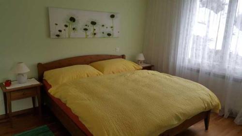 1 dormitorio con 1 cama con manta amarilla en Rigiana auf der Königin der Berge, en Rigi Kaltbad