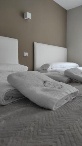 - une chambre avec 2 lits avec des couvertures blanches dans l'établissement Pensión NAVIA A Pontenova, à A Pontenova