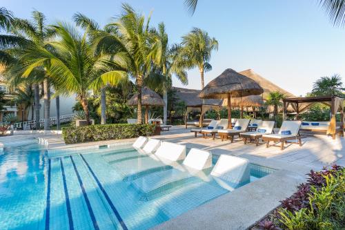 TRS Yucatan Hotel - Adults Only في أكومال: مسبح في منتجع فيه كراسي ومظلات