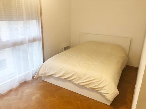 ein weißes Bett in einem Zimmer mit Fenster in der Unterkunft La suite Prestige de Saint Cyr in Saint-Cyr-lʼÉcole