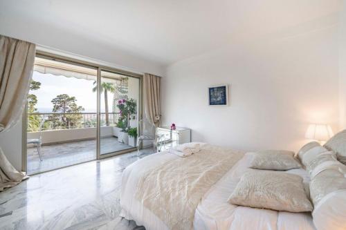 une chambre blanche avec un grand lit et un balcon dans l'établissement Bright one-bedroom in a quiet area wswimming pool, à Cannes