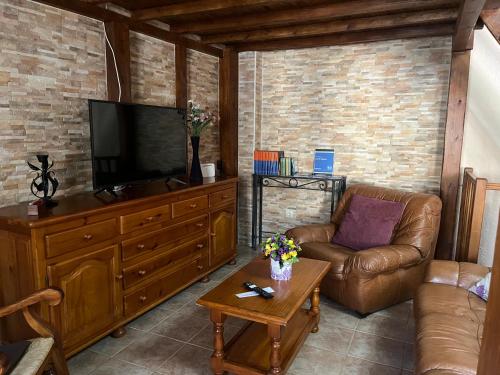 uma sala de estar com um sofá e uma televisão de ecrã plano em Casa del Espliego 