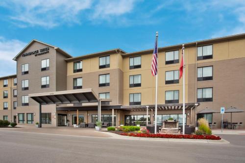 a hotel with two american flags in front of it at TownePlace Suites by Marriott Detroit Belleville in Belleville