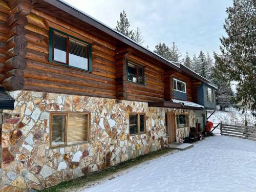 a log cabin with snow on the ground in front of it at Basement Suite on a Goat Farm in Rossland