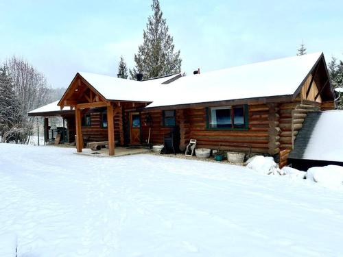 a log cabin in the snow with snow at Basement Suite on a Goat Farm in Rossland