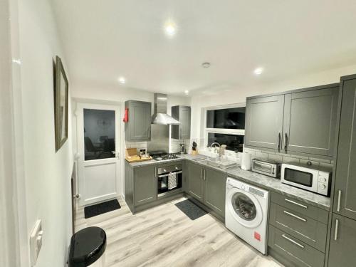 a kitchen with gray cabinets and a washer and dryer at Swindon 3 bedroom relaxing home with parking - good location for family or contractors in Swindon