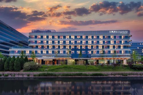 un immeuble de bureaux avec une réflexion dans l'eau dans l'établissement Fairfield by Marriott Beijing Daxing Airport, à Pékin