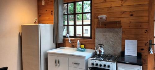フロリアノポリスにあるTiny House Novas Palmeirasのキッチン(白い冷蔵庫、コンロ付)