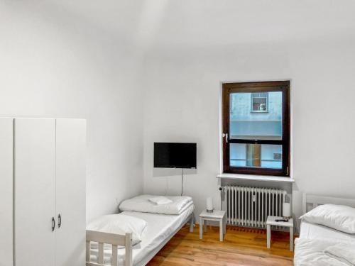 Habitación blanca con 2 camas y ventana en CityChalet Monteur Apartments, en Saarbrücken