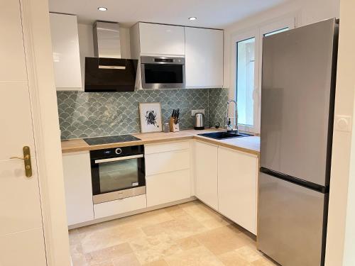 une cuisine avec des armoires blanches et un réfrigérateur en acier inoxydable dans l'établissement Charming house 2BR, 100m to RER B Laplace station, à Arcueil