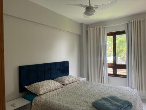 a bedroom with a bed with a large window at Lindo apto no Condomínio Enseada Praia do Forte in Mata de Sao Joao