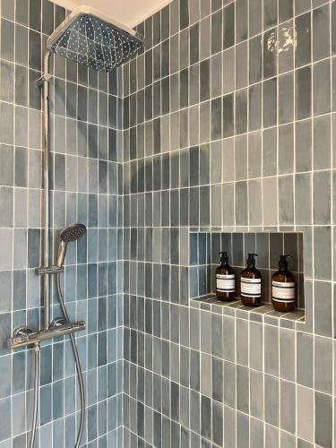 a blue tiled bathroom with three jars on a shelf at Charming house 2BR, 100m to RER B Laplace station in Arcueil