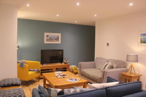 a living room with a couch and a tv at Stylish flat in central Tenby & free parking in Tenby