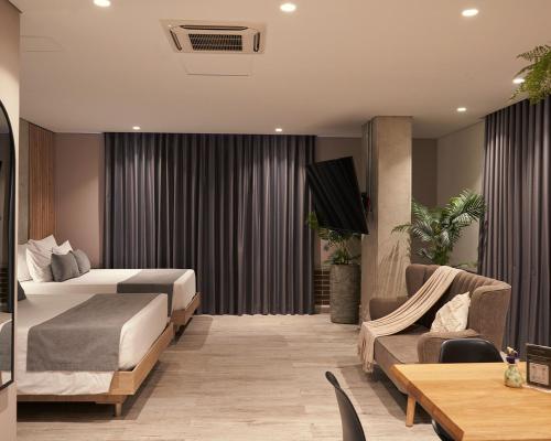 a hotel room with two beds and a couch at Eutopiq Hotel in Medellín