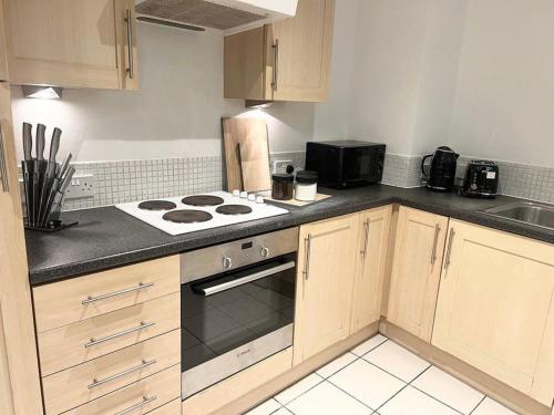 a kitchen with wooden cabinets and a stove top oven at 2 Bedroom city center apartment in Manchester