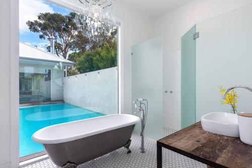 a bathroom with a tub and a swimming pool at Point Leo Luxury Beach House - Point Leo in Shoreham