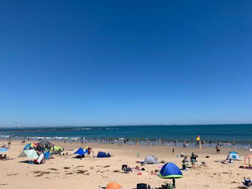 a group of people on a beach with umbrellas at Point Leo Luxury Beach House - Point Leo in Shoreham